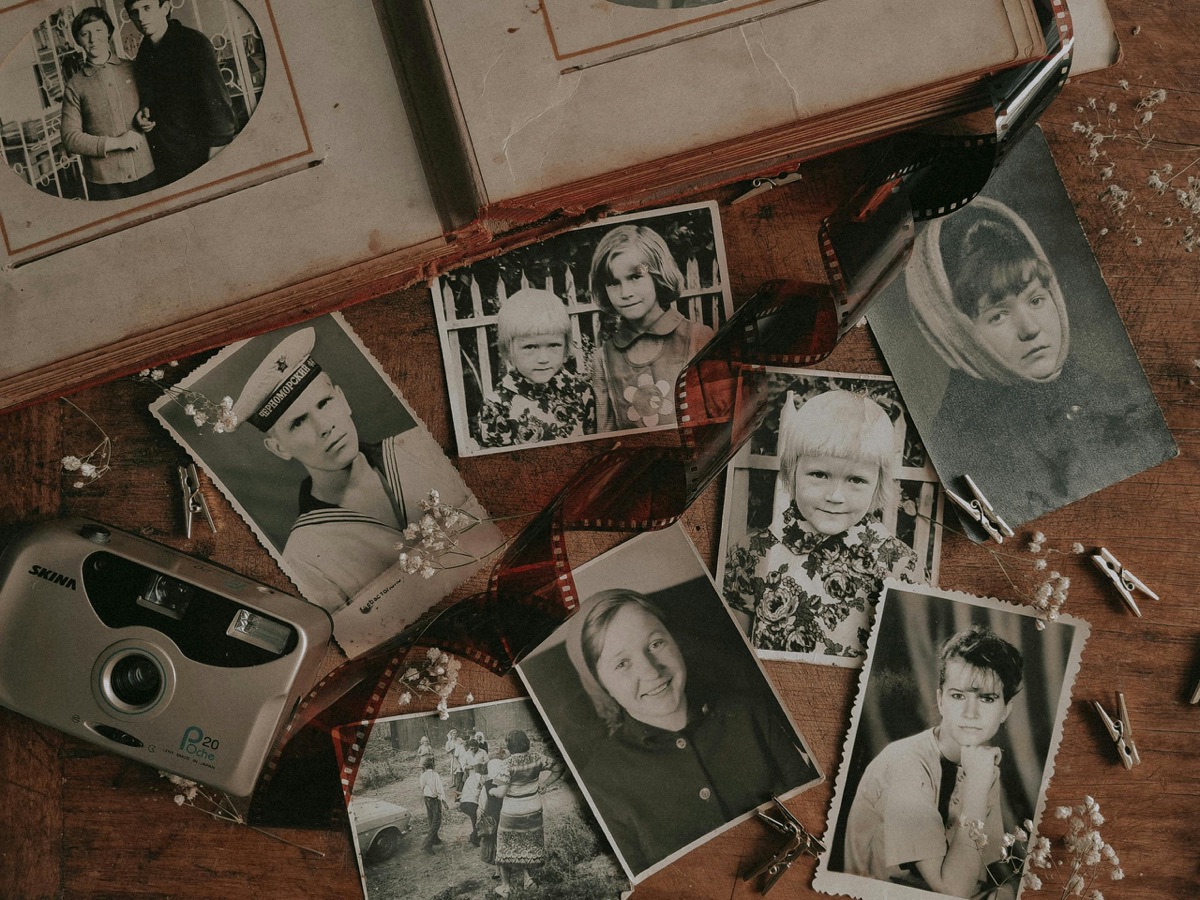 Black-and-white prints, negatives and a vintage camera laid out on a table