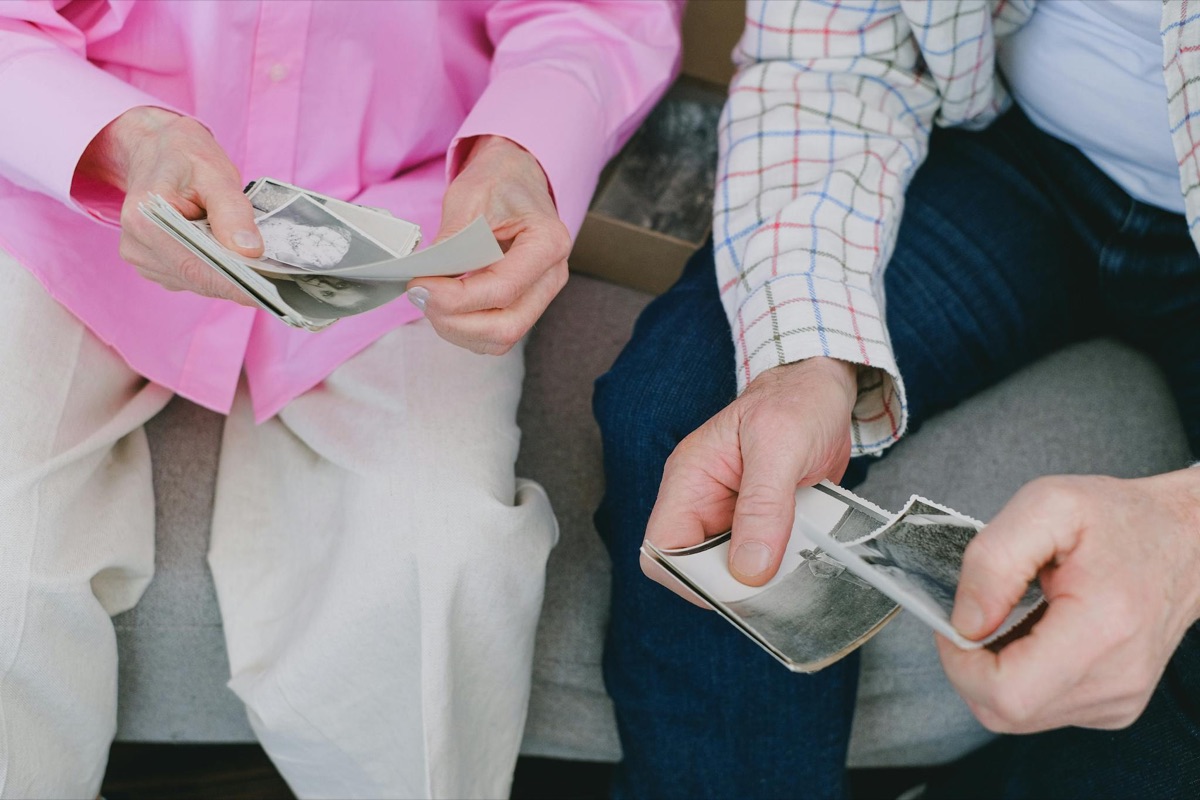 Two people sharing and reminiscing over a handful of old family photographs