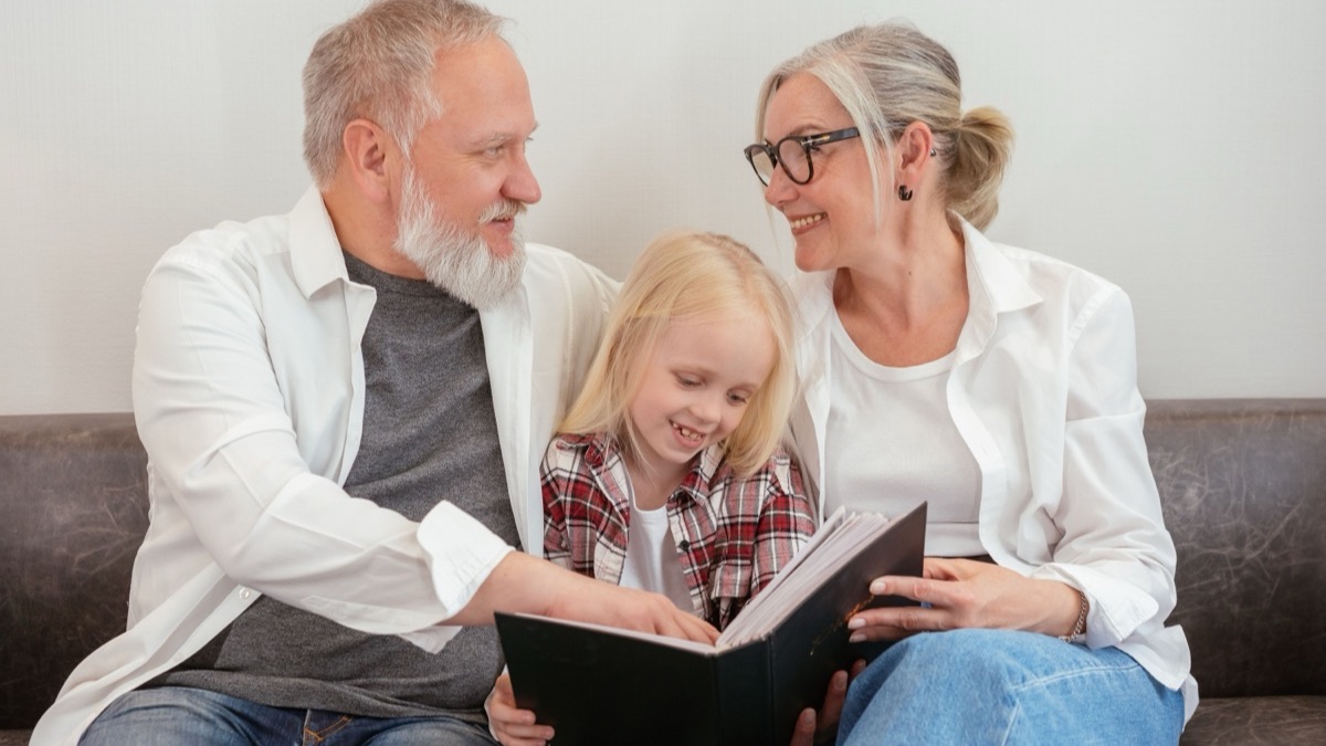 Three generations of a family smiling as they look through an old photo album together